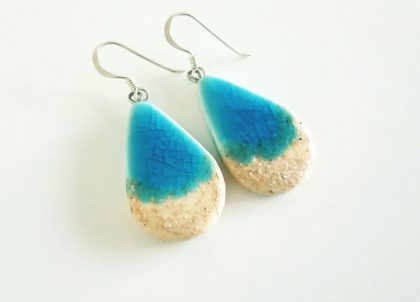 Estas piezas en forma de gota de agua han sido elaboradas en arcilla blanca y esmaltadas con  turquesa cristalino y un efecto de arena blanca que recuerdan las playas vírgenes de la isla montadas engancho de plata AG925..